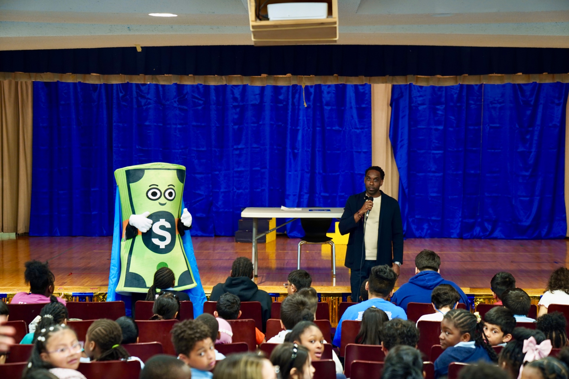 Dave Alexandre presenting with the Captain Cash mascot at a school assembly