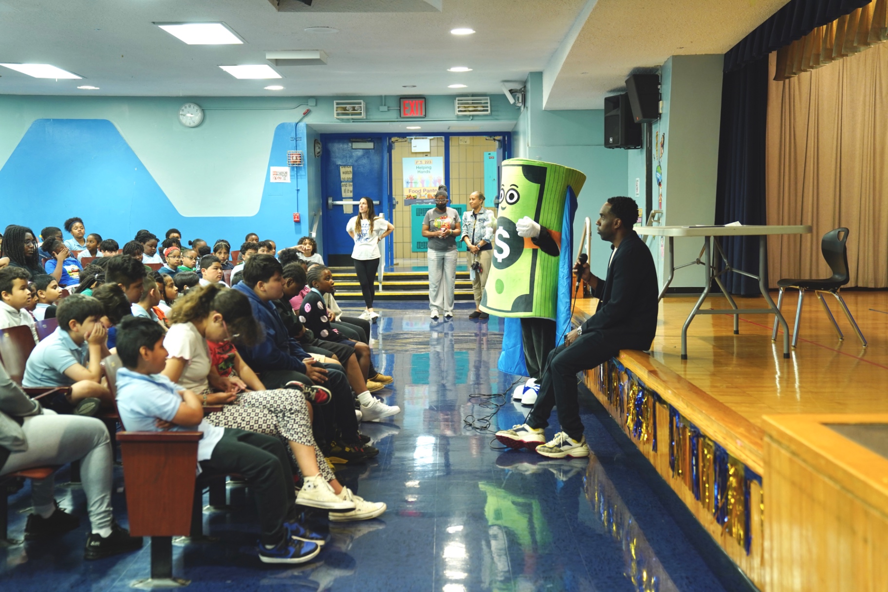 Students listening to Dave Alexandre and Captain Cash in a school auditorium